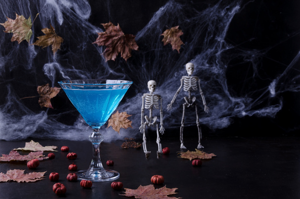 Halloween-Cocktail. Festlicher Umtrunk. Halloween-Party. Kürbisse, Spinnennetze, Skelette auf dunklem Hintergrund in einem dunklen Schlüssel. Selektiver Fokus - Foto, Bild