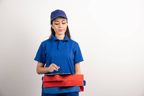 Žena kurýr při pohledu na karton pizzy a schránky  - Fotografie, Obrázek