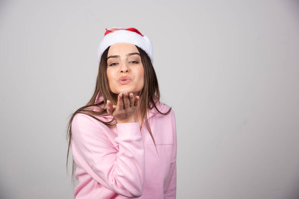 Photo of pretty lady in Santa's hat sending air kiss open palm. High quality photo - Photo, Image