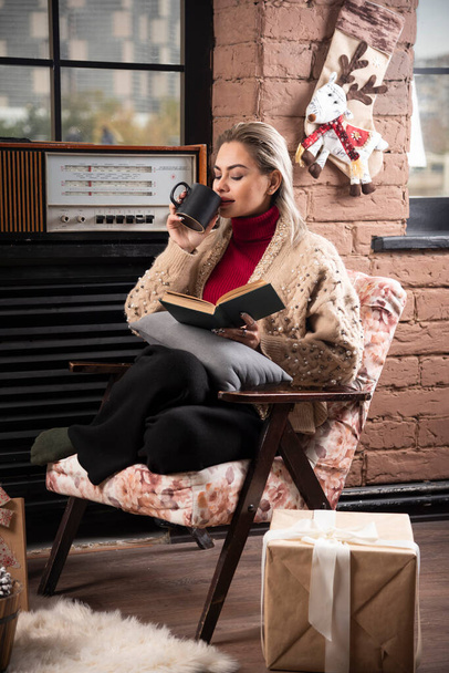 Kobieta siedząca i czytająca książki i pijąca kawę lub herbatę. Wysokiej jakości zdjęcie - Zdjęcie, obraz