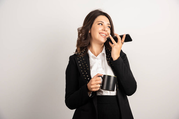 Kobieta trzyma filiżankę herbaty i telefon. Wysokiej jakości zdjęcie - Zdjęcie, obraz