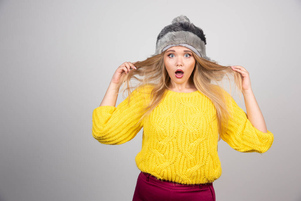 Beautiful woman in yellow sweater acts surprised. High quality photo - Foto, Bild