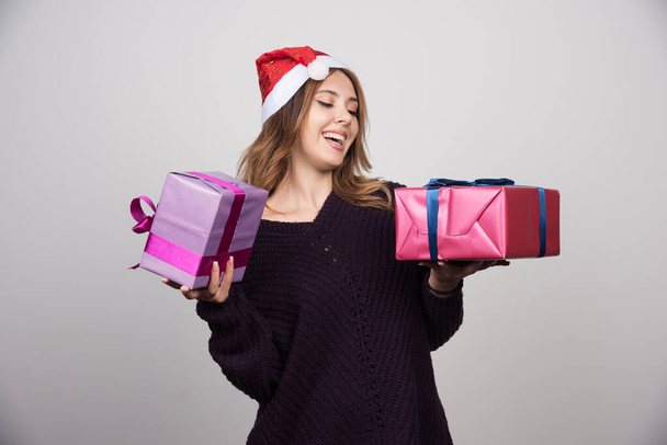 Young woman with Santa hat holding gift boxes presents. High quality photo - Photo, Image