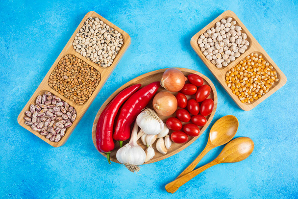 Variety of spices, vegetables and raw beans on blue background. High quality photo - Photo, Image