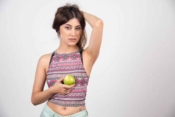 Μια γοητευτική νεαρή γυναίκα που κρατάει ένα πράσινο φρέσκο μήλο. Υψηλής ποιότητας φωτογραφία - Φωτογραφία, εικόνα