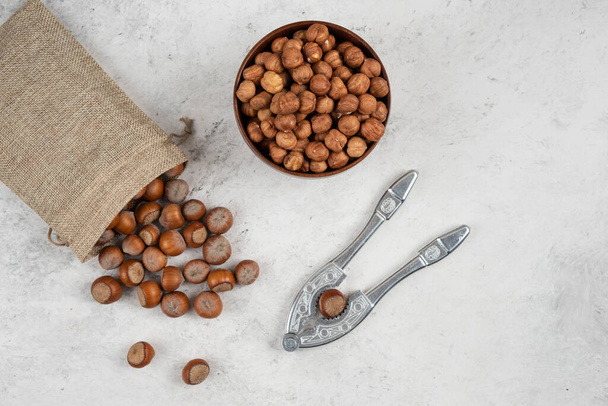 Organic shelled and kernels of hazelnuts in burlap with cracking tool. High quality photo - Valokuva, kuva