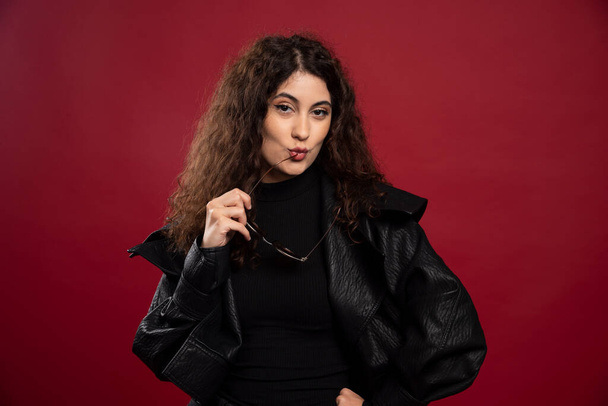 Woman in all black outfit holding glasses and posing. High quality photo - Zdjęcie, obraz