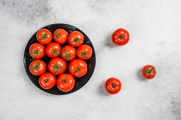 Frische rote Tomaten auf einem schwarzen Teller. Hochwertiges Foto - Foto, Bild