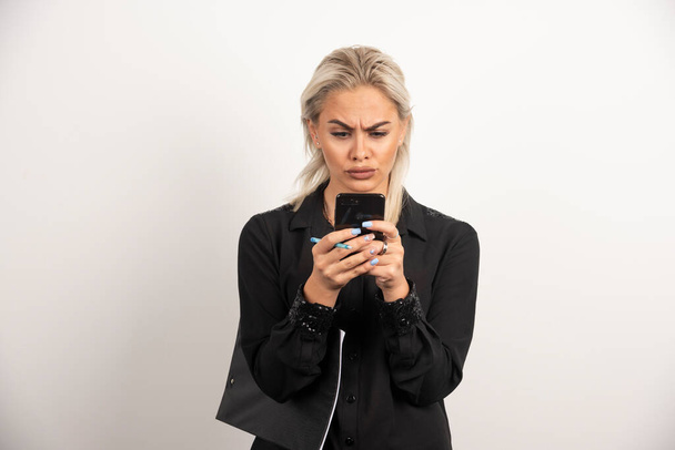 Mujer mirando en el teléfono móvil y sosteniendo un portapapeles. Foto de alta calidad - Foto, Imagen