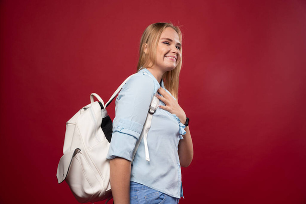 Young schoolgirl wearing a backpack looks positive and fun. High quality photo - Photo, image