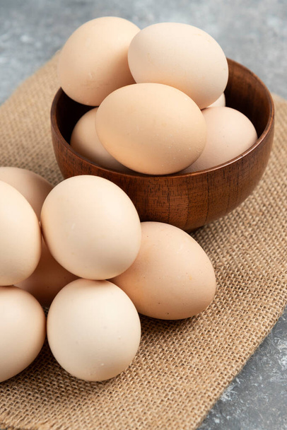 Mermer yüzeyde tahtadan bir kase organik çiğ yumurta. Yüksek kalite fotoğraf - Fotoğraf, Görsel