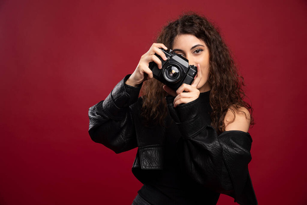 Naisvalokuvaaja mustissa vaatteissa ottamassa kuvia kameralla. Laadukas kuva - Valokuva, kuva