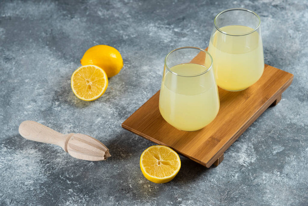 Cups full of lemonade with slices of lemon and wooden reamer. High quality photo - Foto, immagini