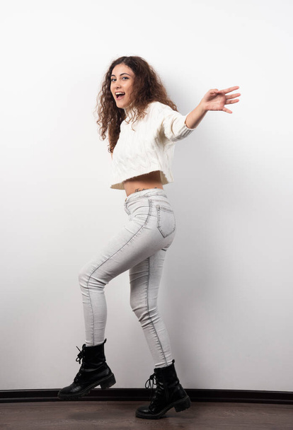 Mujer joven en suéter blanco de pie sobre una pared blanca. Foto de alta calidad - Foto, imagen