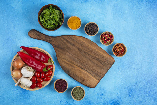 Various spices around wooden board with plate of vegetables. High quality photo - Fotografie, Obrázek