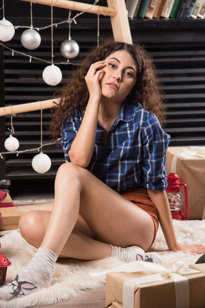 Nuori nainen istuu ja poseeraa joulun sisustuksessa. Laadukas kuva - Valokuva, kuva