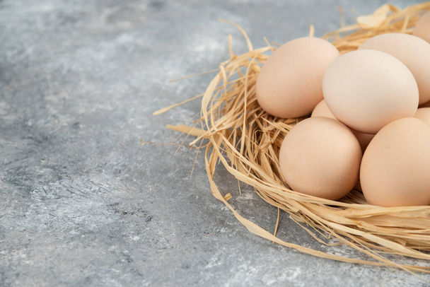 Mazzo di uova crude con nido d'uccello sulla superficie di marmo. Foto di alta qualità - Foto, immagini