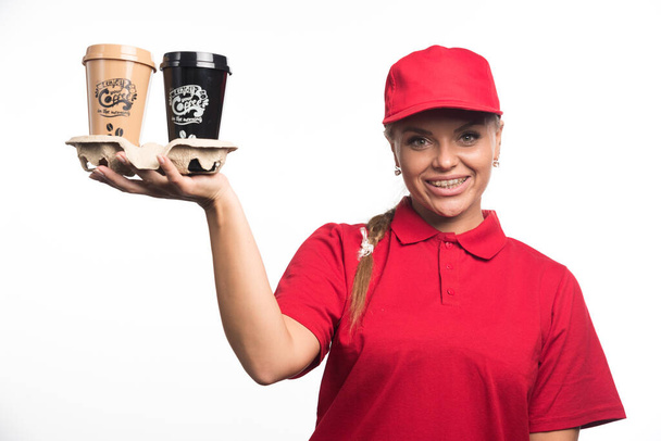 Frau in roter Uniform mit zwei Tassen Kaffee auf weißem Hintergrund  - Foto, Bild