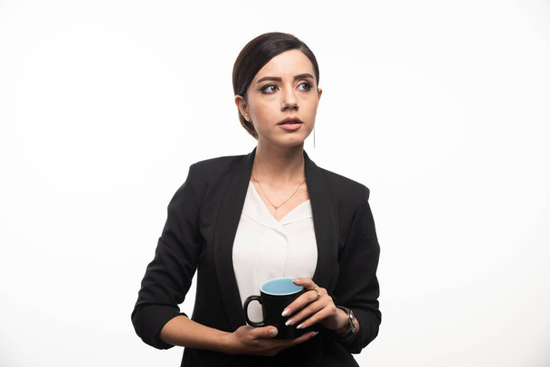 Una mujer en traje con una taza de café en la mano sobre fondo blanco. Foto de alta calidad - Foto, Imagen