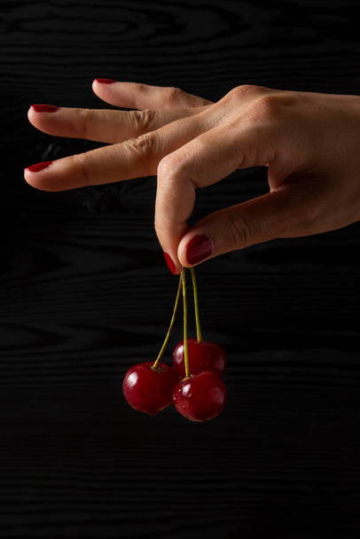 hand holding cherries on wooden background - Photo, Image