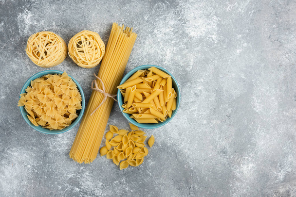 Сырая паста и сорта спагетти на мраморном фоне. Высокое качество фото - Фото, изображение