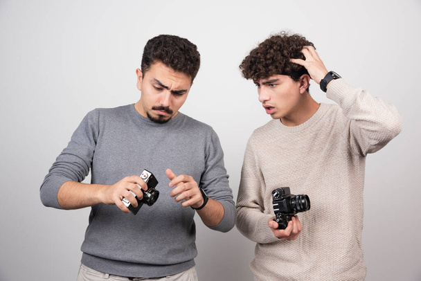 Two young men holding cameras on a white background. High quality photo - Photo, Image