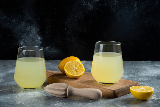 Two glass cups of fresh lemon juice and wooden reamer. High quality photo - Photo, Image