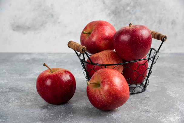 Manzanas rojas orgánicas maduras en canasta de metal sobre fondo negro. Foto de alta calidad - Foto, Imagen