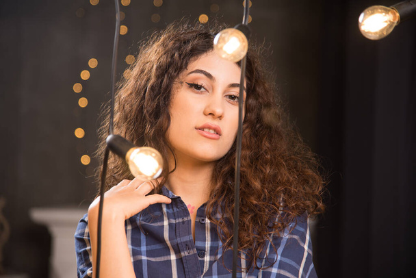 Egy fiatal modell portréja kockás ingben, lámpák mellett pózolva. Kiváló minőségű fénykép - Fotó, kép