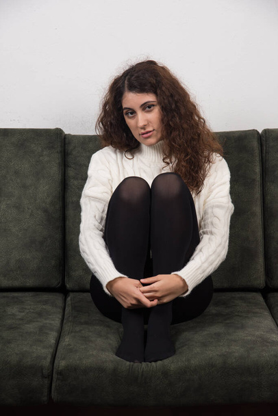 A young woman sitting on her dark green sofa . High quality photo - Foto, Bild
