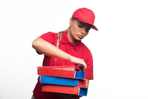 Pizza teslimatçısı kadın beyaz arka planda pizza kutularını açmaya çalışıyor. Yüksek kalite fotoğraf - Fotoğraf, Görsel