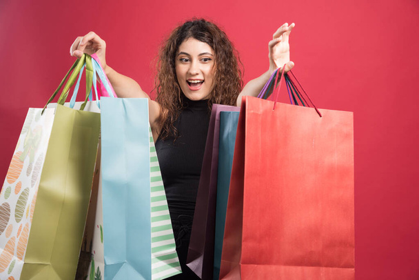 Woman showing her new buying clothes on red background. High quality photo - Photo, image