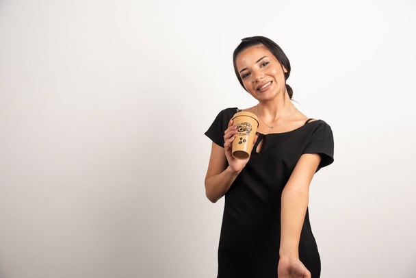 Elegante vrouw met een kop koffie poserend op een witte achtergrond. Hoge kwaliteit foto - Foto, afbeelding