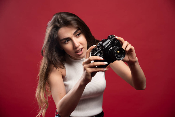 Jolie femme prenant des photos avec un appareil photo sur un fond rouge. Photo de haute qualité - Photo, image