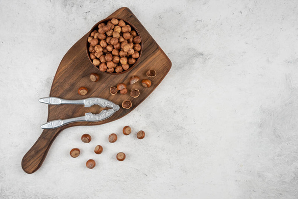 Wooden bowl of unpeeled organic hazelnut kernels on cutting board. High quality photo - Fotoğraf, Görsel