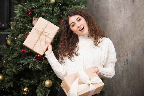 Portrait of young girl with curly hair holding two gifts in a wrapper . High quality photo - Fotografie, Obrázek