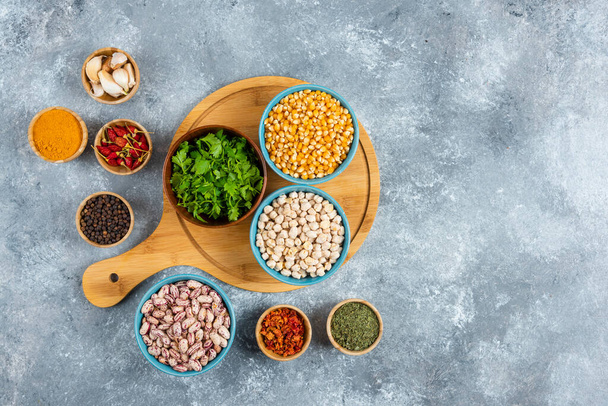 Three bowls of various beans and corns with spices on wooden board. High quality photo - Foto, imagen