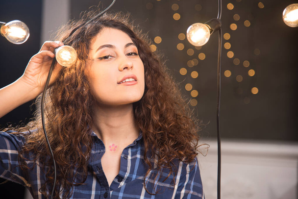Egy fiatal modell portréja kockás ingben, lámpák mellett pózolva. Kiváló minőségű fénykép - Fotó, kép