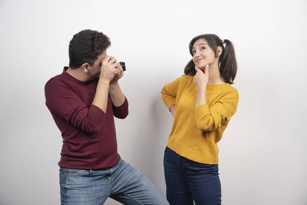 Cute couple taking pictures with camera and posing over a white wall. High quality photo - Photo, Image