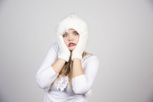 Blonde woman in winter outfit holding her cheeks. High quality photo - Fotografie, Obrázek