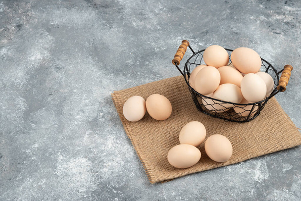 Wicker basket of raw organic eggs on marble background. High quality photo - Zdjęcie, obraz