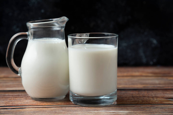 Friss tej egy bögrében és korsó a fa asztalon. Kiváló minőségű fénykép - Fotó, kép