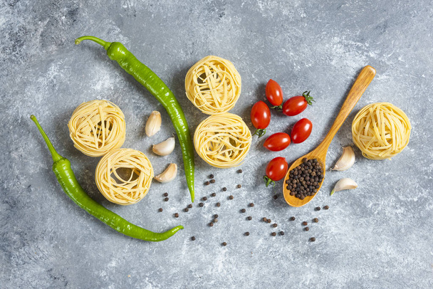 Főzetlen fészekspagetti zöldségekkel márvány alapon. Kiváló minőségű fénykép - Fotó, kép