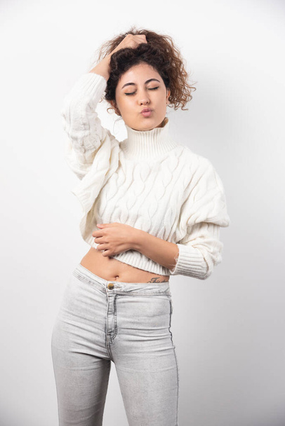 Young woman in white sweater doing funny face over a white wall. High quality photo - 写真・画像