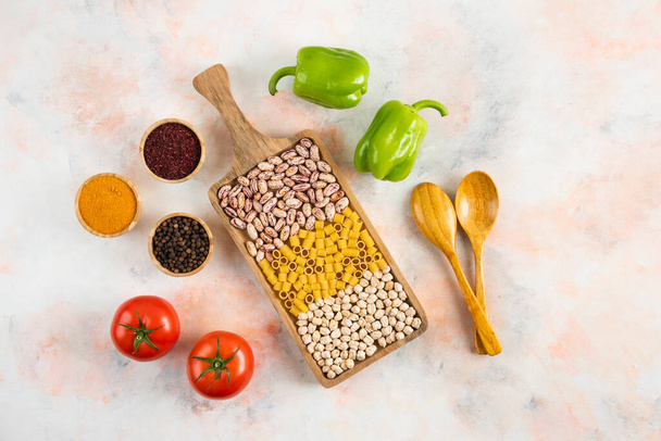 Top view of Bean, pasta and chickpea on wooden tray with fresh vegetable and spices. High quality photo - Photo, Image