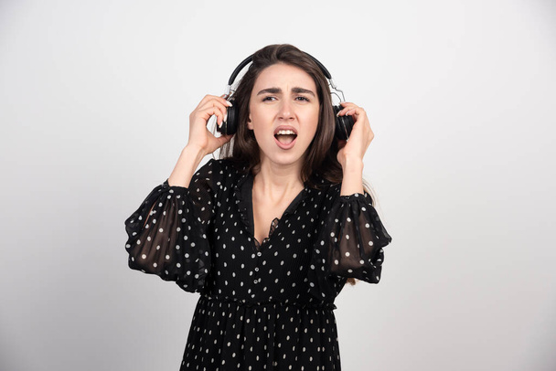 Linda chica escuchando música con sus auriculares sobre un fondo blanco. Foto de alta calidad - Foto, Imagen