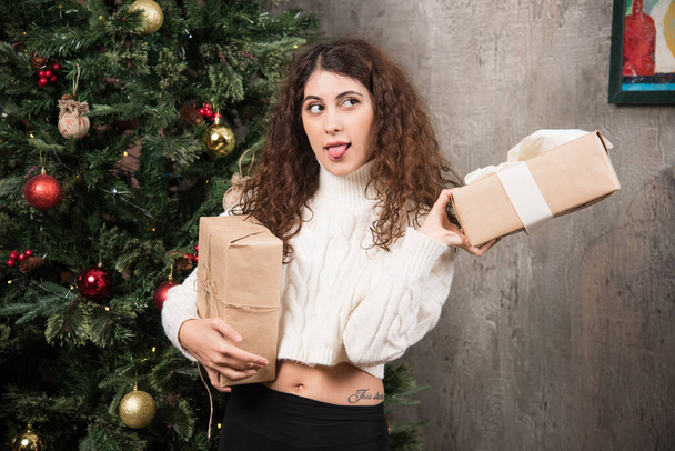 Portrait of young girl with curly hair holding two gifts in a wrapper . High quality photo - Foto, Imagem