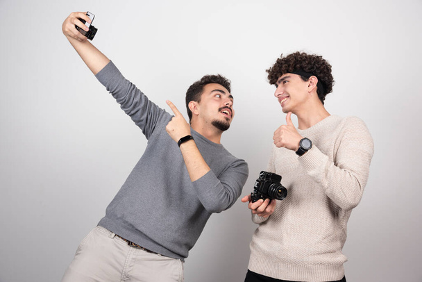 Dois jovens a tirar uma selfie num fundo branco. Foto de alta qualidade - Foto, Imagem