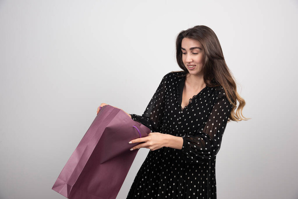 Modelo de mulher jovem olhando no saco de compras em um fundo branco. Foto de alta qualidade - Foto, Imagem
