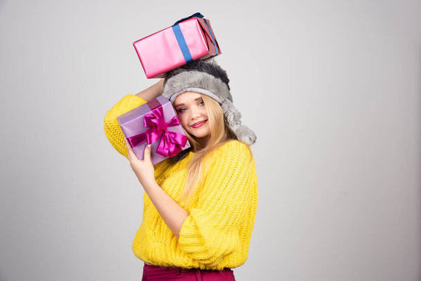 Portrait of happy young woman in cap bringing a load of gifts. High quality photo - Фото, изображение